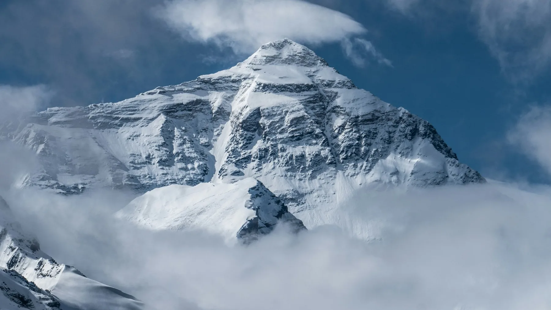 The snow-covered summit of Mount Everest rising above the clouds